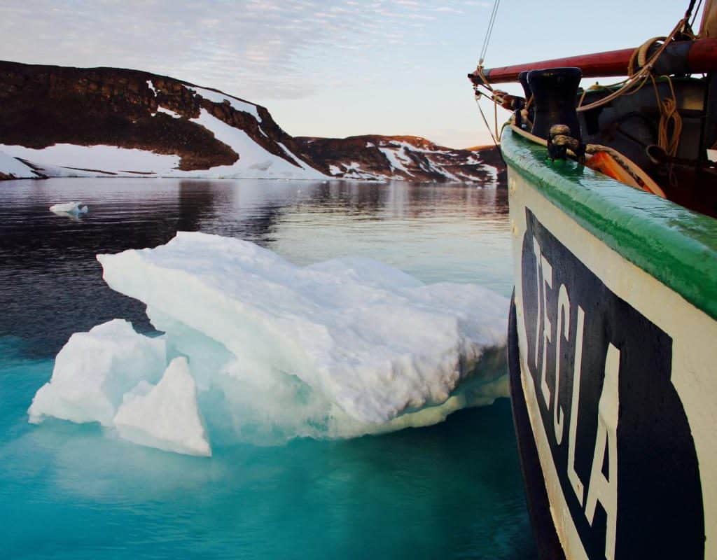 Tecla sailing through icy waters on a Classic Sailing adventure holiday. The nameplate of the ship with the green capping rail can be seen in the bright light as the ship slowly noses through the ice,