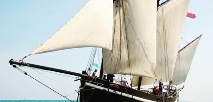 lugger grayhound under full sail on a green sea. sail cargo voyages and adventure holidays with classic sailing