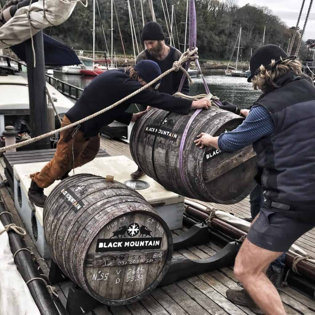 the crew of grayhound loading barrels of rum onto the ship's deck. sail cargo voyages and adventure holidays with classic sailing