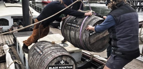 the crew of grayhound loading barrels of rum onto the ship's deck. sail cargo voyages and adventure holidays with classic sailing