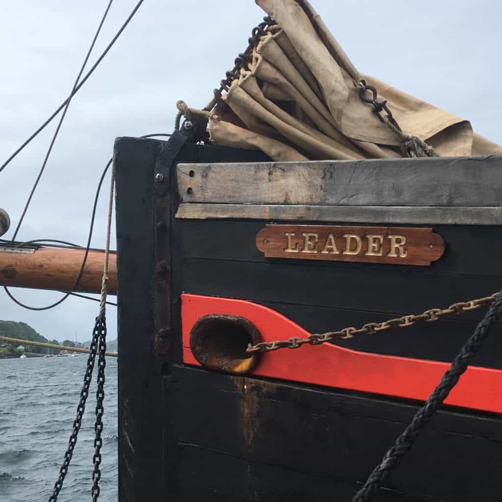 The nameplate at the bow of Leader. Black hull with a red stripe, and wooden name plate.