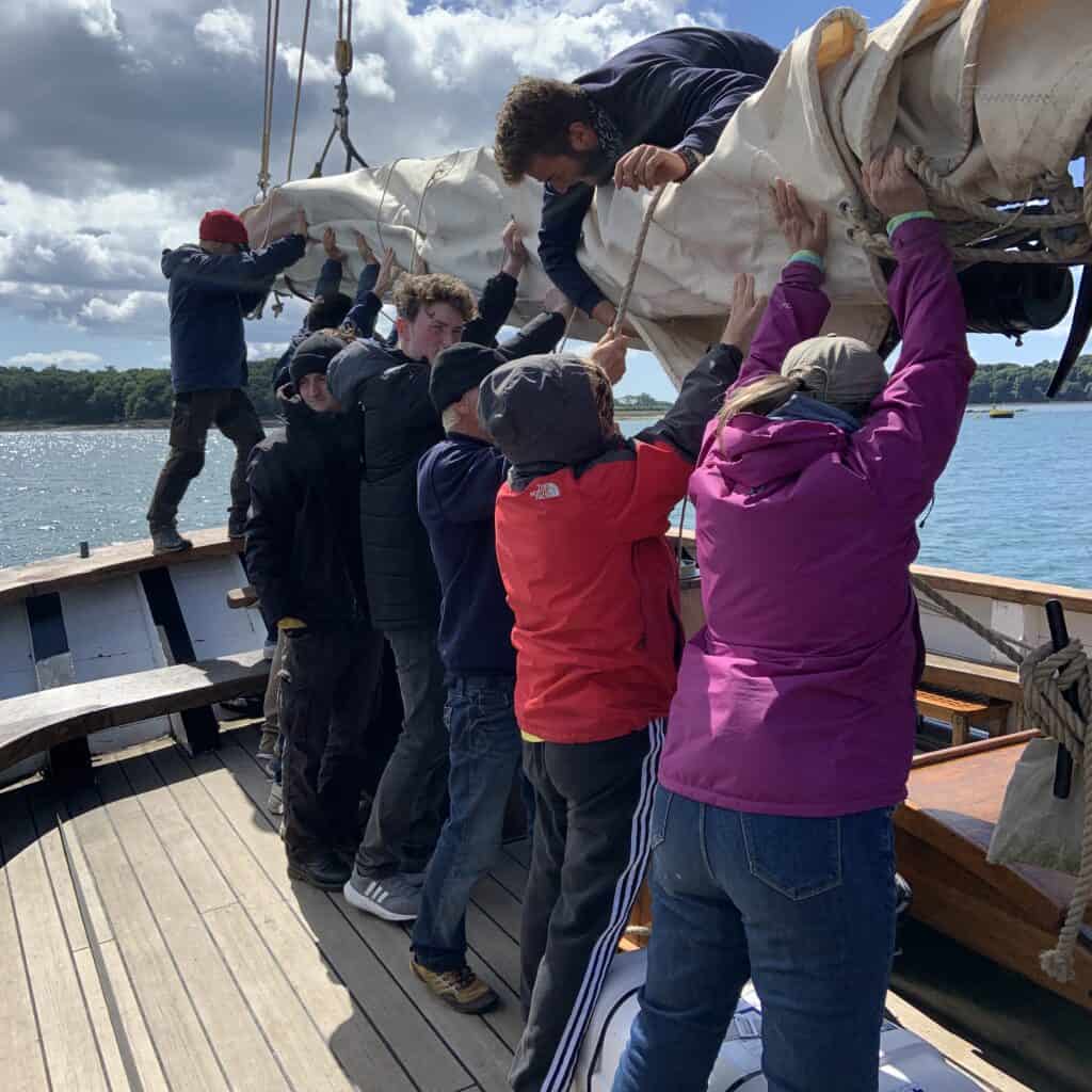 Crew and guests furling the mizzen sail on Leader