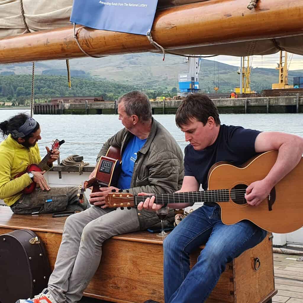 Crew playing guitar on the deck of sailing ship Leader