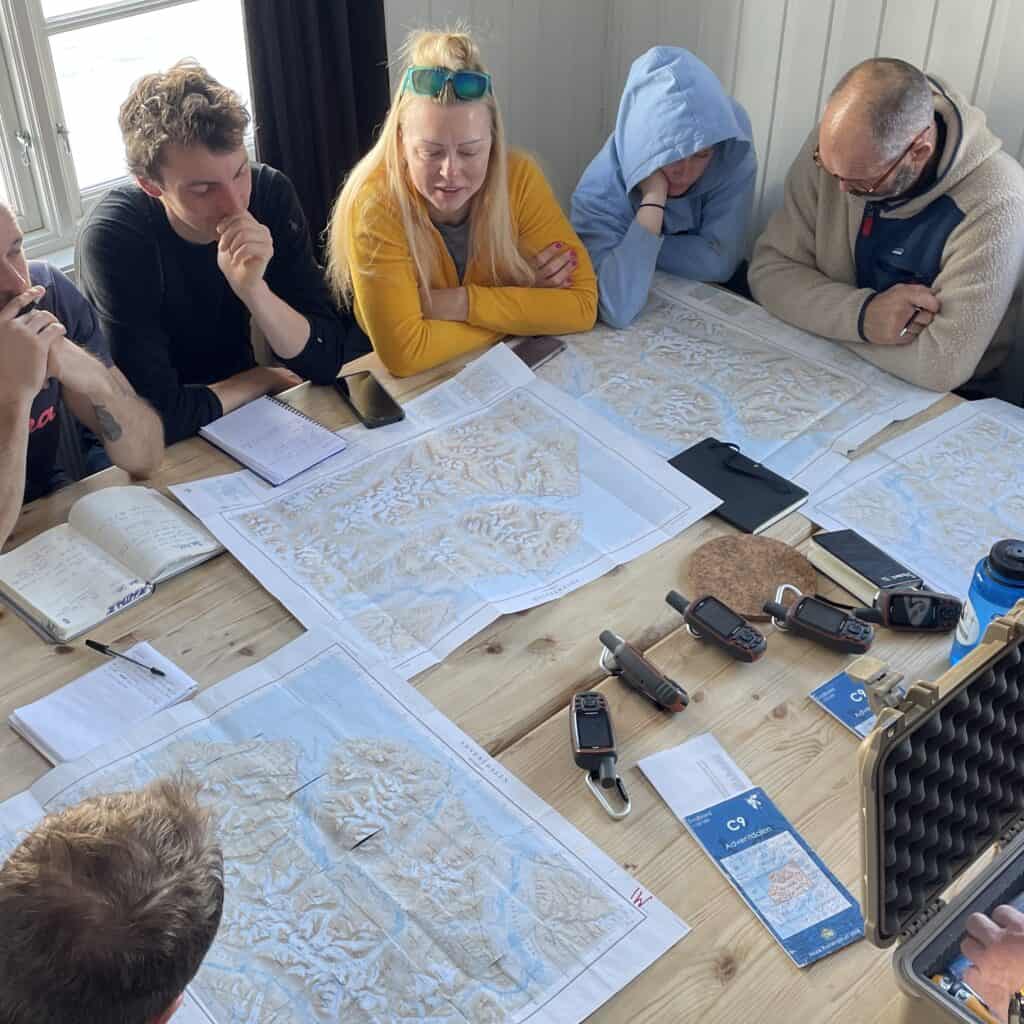 Polar explorer Jim McNeill leads an Ocean warrior planning meeting. A group poring over maps. Join the adventure through Classic Sailing