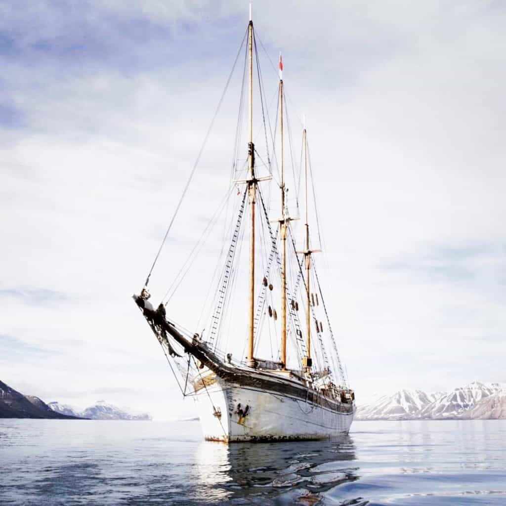 Expedition ship Linden anchored in the sunshine off Svalbard. Join an arctic voyage with Classic Sailing.