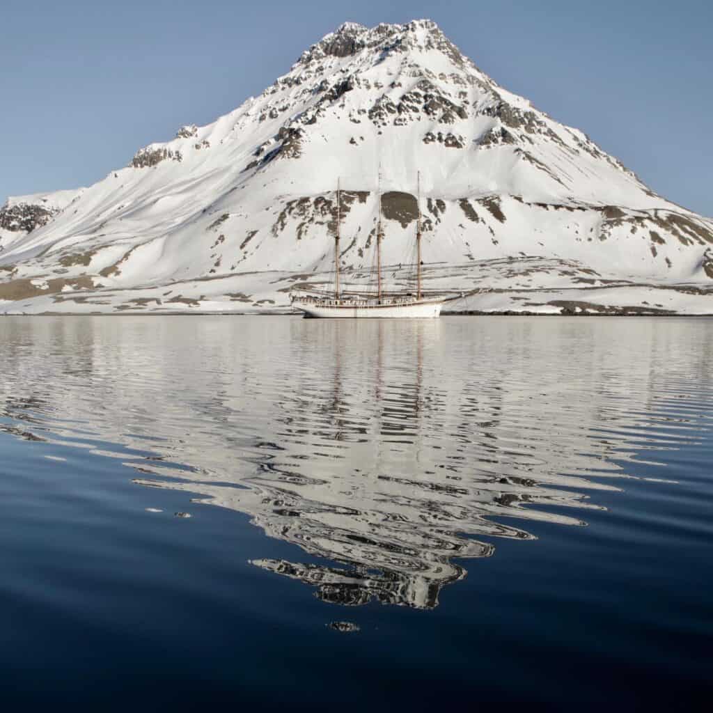 Linden anchored in front of a snowy peak on Svalbard. Have a real adventure with a research expedition through Classic Sailing.