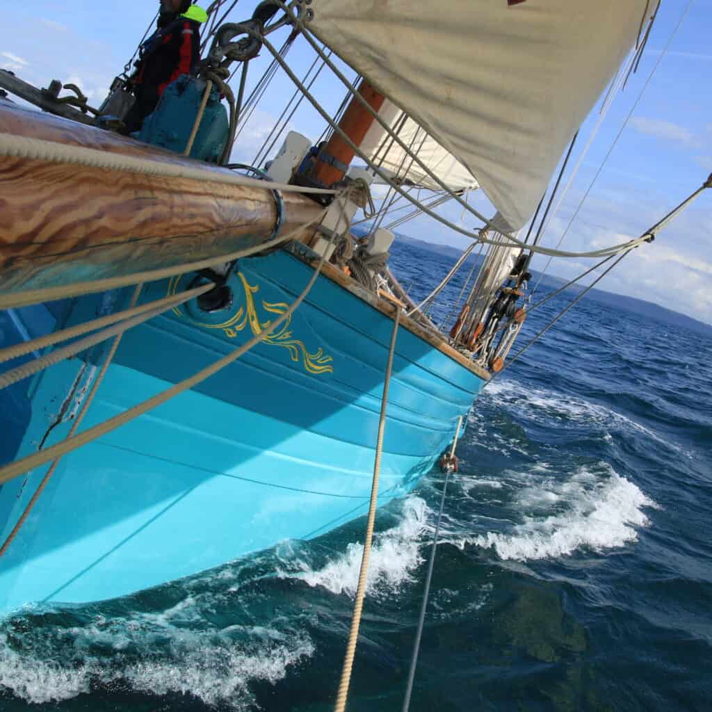 bowsprit view of pilot cutter Tallulah. spring sail with paintwork colour matching the turquoise seas