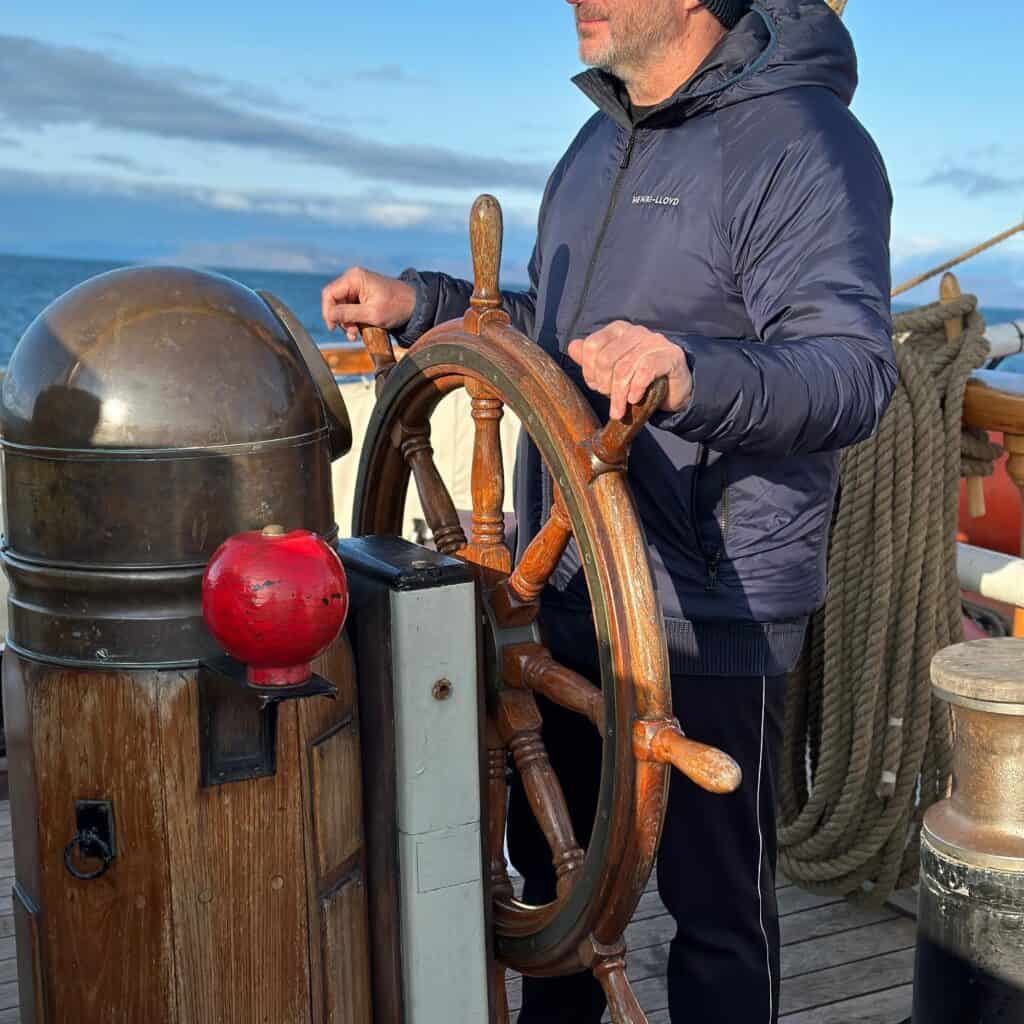 Jim on the helm of Linden. Ocean Warrior #Resolute Expedition with Classic Sailing. Jim is wearing Henry Lloyd kit.